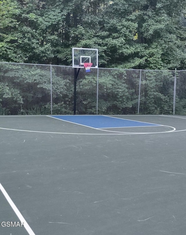 view of sport court featuring basketball hoop and fence