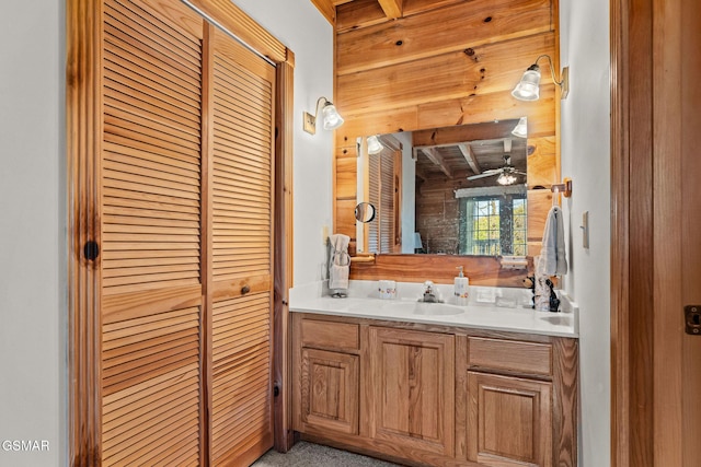 bathroom featuring a closet, vanity, ceiling fan, beamed ceiling, and wood walls