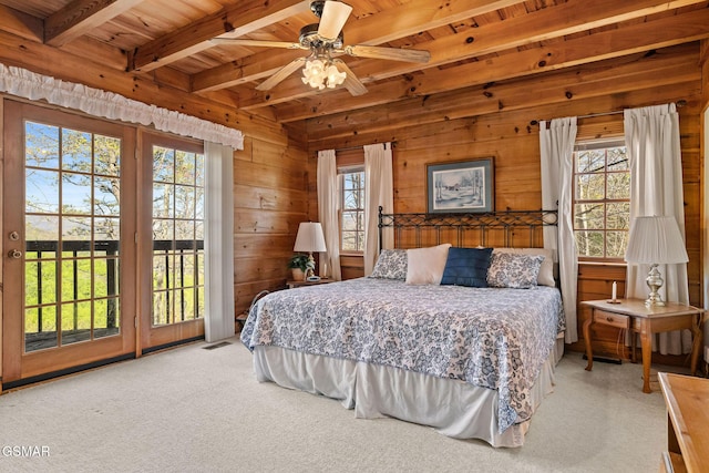 carpeted bedroom with wood walls, access to exterior, visible vents, beam ceiling, and wood ceiling