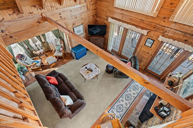 living room featuring a high ceiling, wooden walls, wood finished floors, and a wealth of natural light