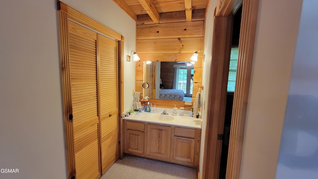 ensuite bathroom with wood walls, vanity, ensuite bath, wooden ceiling, and beamed ceiling