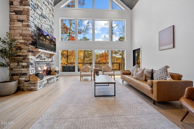 unfurnished living room with a stone fireplace, plenty of natural light, and a high ceiling