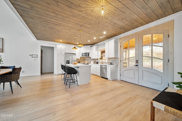 kitchen with appliances with stainless steel finishes, a center island, hanging light fixtures, and wooden ceiling