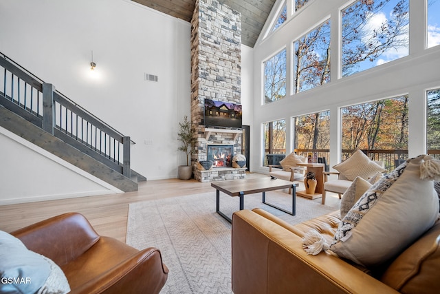 living room with a fireplace, high vaulted ceiling, and light hardwood / wood-style floors