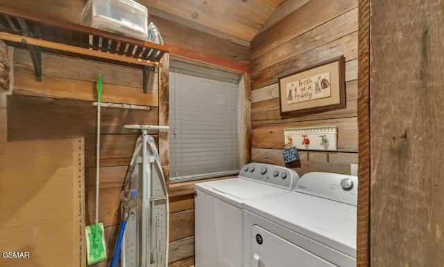 clothes washing area with washer and clothes dryer and wood walls