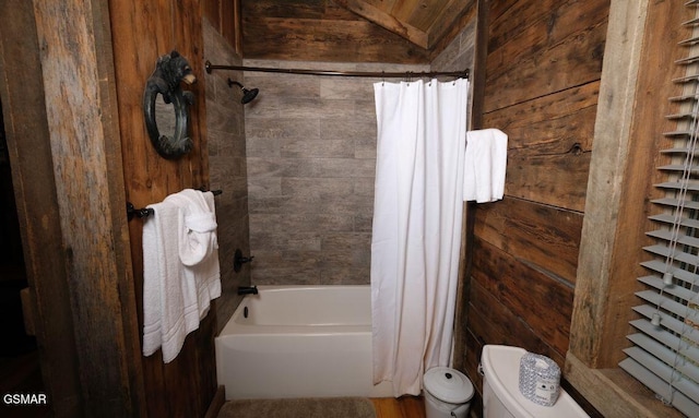 bathroom featuring lofted ceiling, wooden walls, shower / bath combo, and toilet