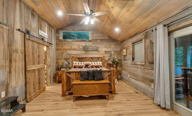 bedroom with a barn door, wood walls, light hardwood / wood-style floors, lofted ceiling, and wood ceiling