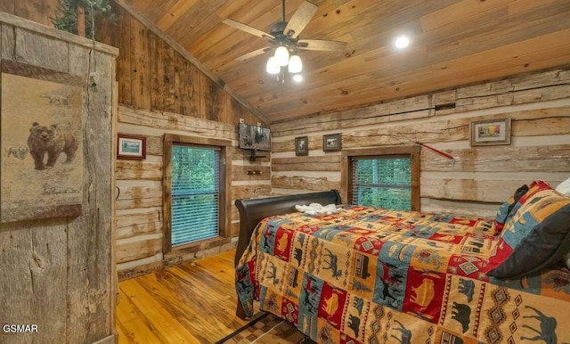 bedroom featuring ceiling fan, wood-type flooring, wooden walls, and lofted ceiling