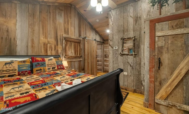 bedroom featuring ceiling fan, wood walls, vaulted ceiling, wood ceiling, and light wood-type flooring