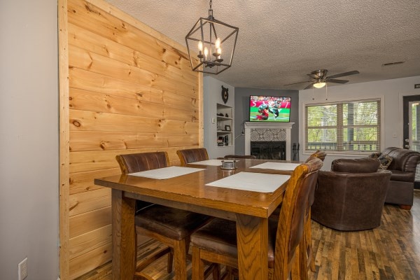 dining room with ceiling fan with notable chandelier, a textured ceiling, hardwood / wood-style flooring, and wooden walls