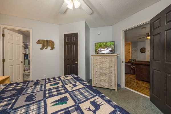 carpeted bedroom with ensuite bathroom and ceiling fan