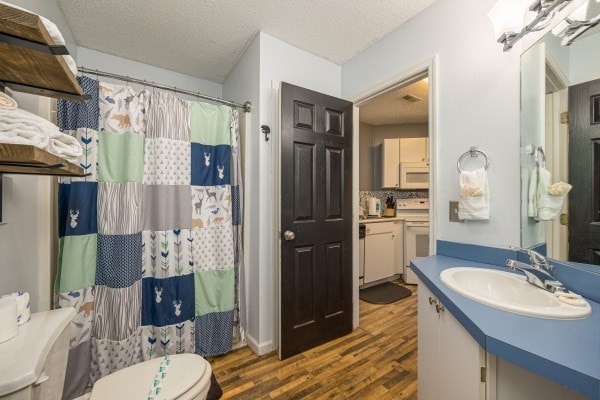 bathroom featuring hardwood / wood-style floors, a textured ceiling, toilet, decorative backsplash, and vanity