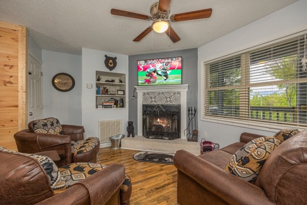 living room with ceiling fan, built in features, a textured ceiling, and hardwood / wood-style flooring