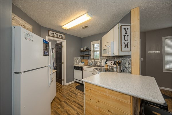 kitchen with a textured ceiling, white cabinetry, sink, and white appliances