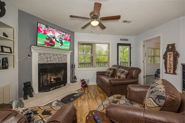 living room featuring hardwood / wood-style floors, ceiling fan, and a textured ceiling