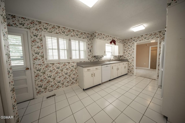 kitchen featuring a textured ceiling, white cabinets, sink, light tile patterned flooring, and white dishwasher