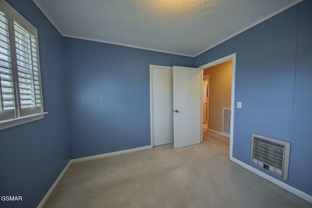 unfurnished room with heating unit, light colored carpet, a textured ceiling, and ornamental molding