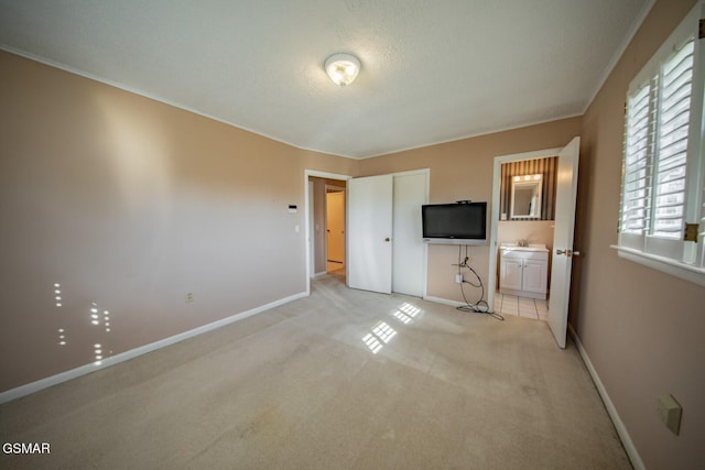 unfurnished bedroom featuring ensuite bathroom, light carpet, sink, and multiple windows