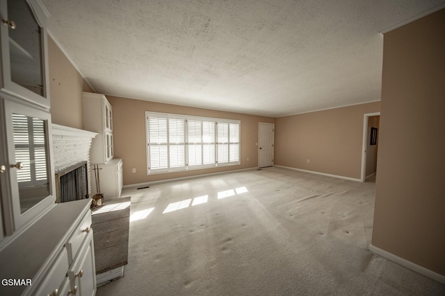 unfurnished living room with a brick fireplace, light colored carpet, and a textured ceiling