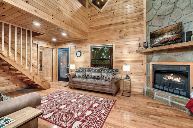 living room with hardwood / wood-style flooring, a fireplace, and wooden walls