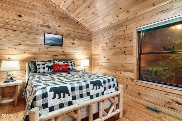 bedroom featuring vaulted ceiling, wooden ceiling, wood walls, and light wood-type flooring