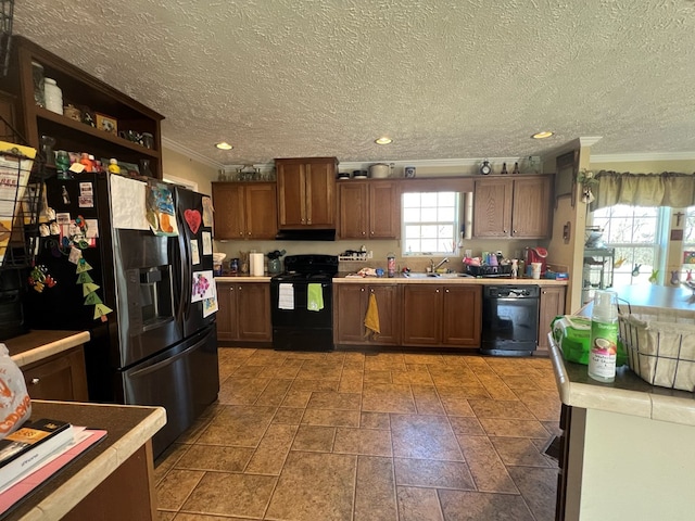 kitchen with a textured ceiling, sink, ornamental molding, and black appliances