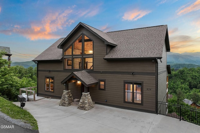 back of property with a patio area, a mountain view, and roof with shingles