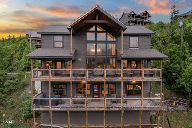 back of property at dusk with a shingled roof