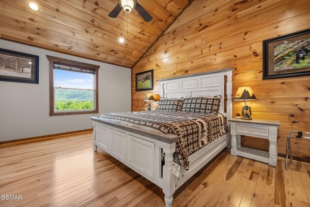 bedroom featuring wooden walls, baseboards, lofted ceiling, light wood-style flooring, and wood ceiling