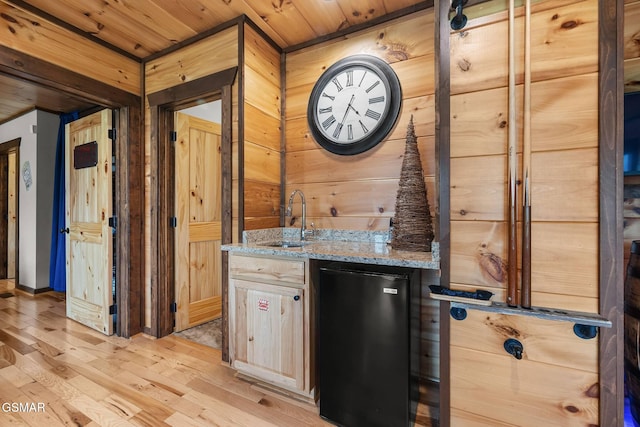 bar featuring a sink, fridge, wooden walls, wooden ceiling, and light wood finished floors