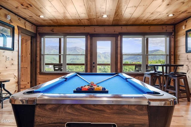 playroom with wooden ceiling, a mountain view, wood walls, and light wood-type flooring