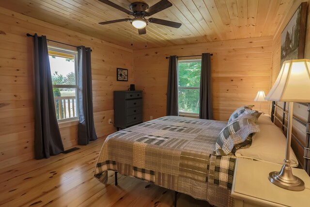 bedroom featuring hardwood / wood-style flooring, ceiling fan, wood walls, and wooden ceiling