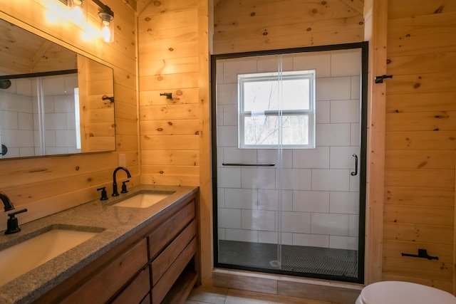 bathroom featuring tile patterned flooring, wood walls, toilet, vanity, and a shower with shower door