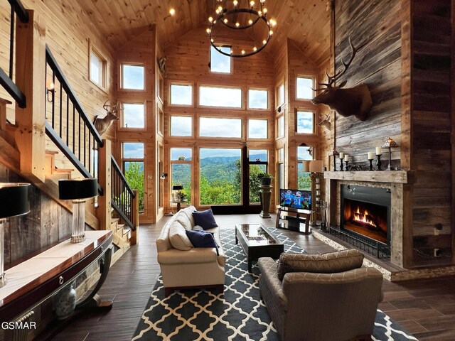 1642 Little Cove Rd, Sevierville, TN 37862 - living room featuring high vaulted ceiling, wood finished floors, a stone fireplace, wooden walls, and stairs