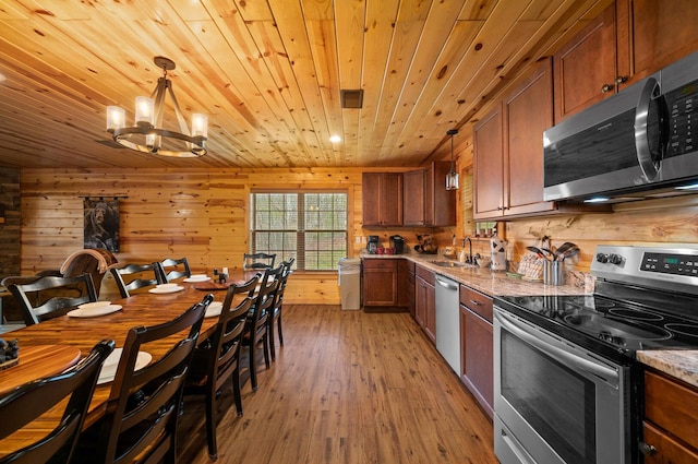 kitchen featuring brown cabinets, a sink, appliances with stainless steel finishes, light wood finished floors, and wood ceiling