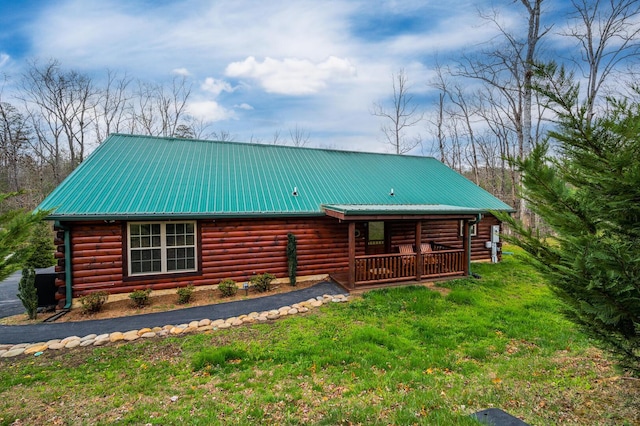 exterior space featuring log exterior, covered porch, a yard, and metal roof