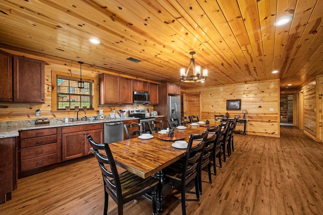 dining space with wooden ceiling, wood finished floors, visible vents, and wood walls