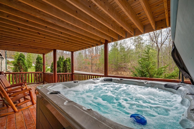 wooden deck featuring a forest view and a hot tub