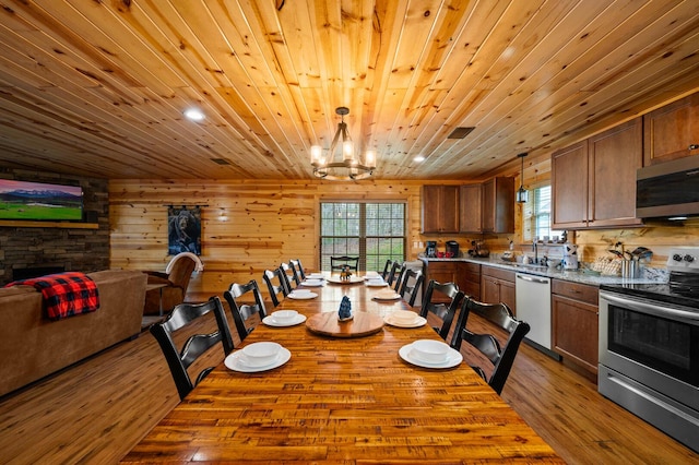 dining space featuring visible vents, wood walls, wooden ceiling, an inviting chandelier, and wood finished floors