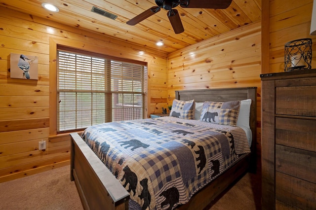 carpeted bedroom featuring visible vents, a ceiling fan, wood walls, and wooden ceiling