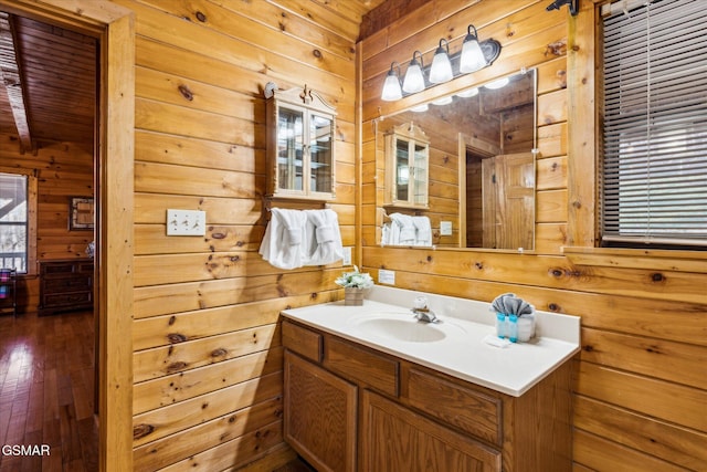 bathroom with hardwood / wood-style flooring, wooden walls, vanity, and beam ceiling