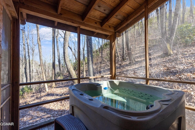 unfurnished sunroom with a view of trees, wooden ceiling, and a hot tub