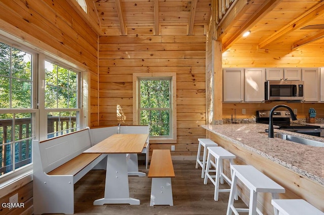 dining room featuring beam ceiling, dark wood-type flooring, and wood ceiling