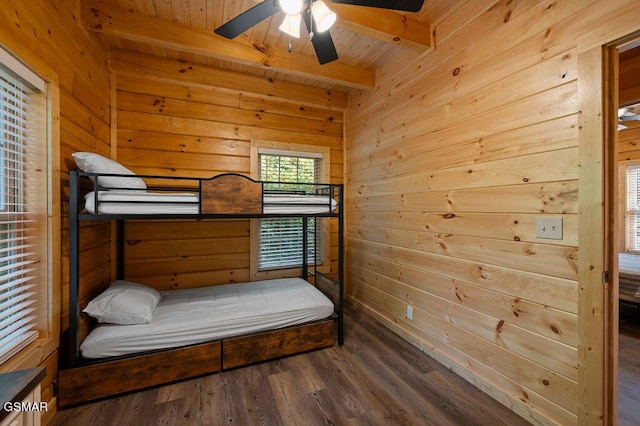 bedroom featuring beam ceiling, ceiling fan, wooden ceiling, hardwood / wood-style floors, and wooden walls