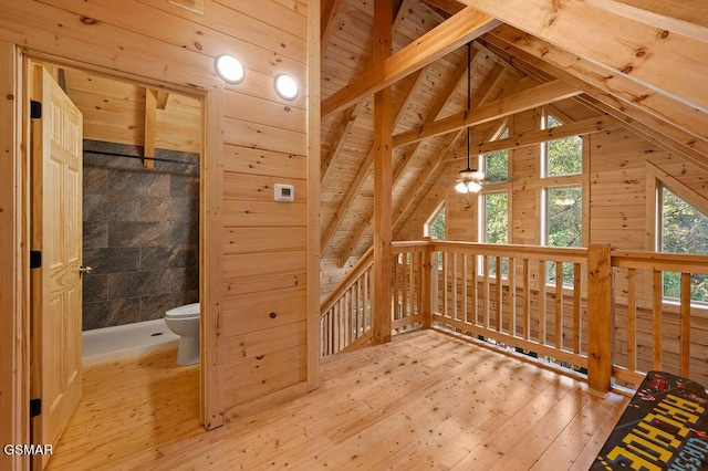 interior space with lofted ceiling with beams, wood walls, light wood-type flooring, and wooden ceiling