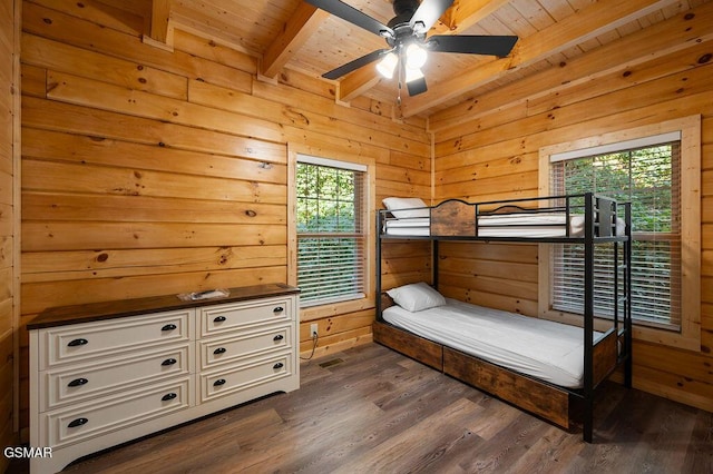 bedroom with wooden walls, dark hardwood / wood-style flooring, beamed ceiling, and wooden ceiling