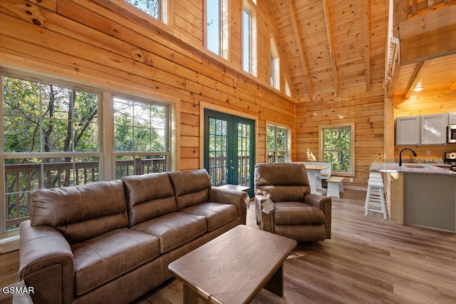 living room featuring wood walls, high vaulted ceiling, french doors, beam ceiling, and wood ceiling