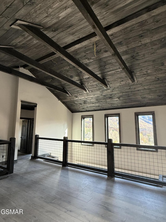 unfurnished room featuring vaulted ceiling with beams, a wealth of natural light, dark hardwood / wood-style flooring, and wood ceiling