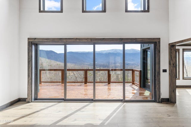 doorway to outside with wood finished floors, a mountain view, and baseboards