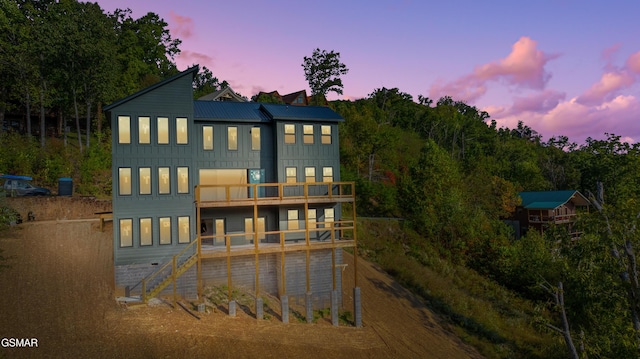 back house at dusk featuring a balcony